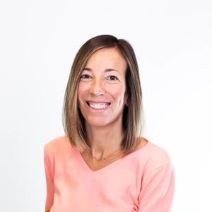 Porträt einer Frau im rosafarbenen Oberteil, die warm in die Kamera lächelt.