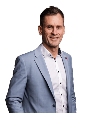 Portrait of a man in a light blue suit, smiling and standing against a light background.