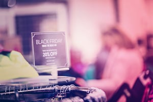 Perchero en tienda de ropa con cartel de Black Friday que ofrece un 20% adicional de descuento.